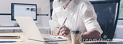 Pensive businessman working at modern coworking office. Confident man using contemporary mobile laptop.Wide.Cropped. Stock Photo