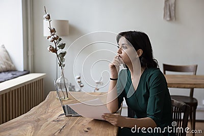 Pensive businesswoman sits at desk ponder received information from document Stock Photo
