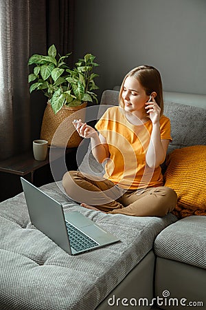 Pensive Caucasian beautiful woman work using laptop headphones remotely from home. Portrait of teenage girl student Stock Photo