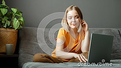 Pensive Caucasian beautiful woman work using laptop remotely from home. Portrait of teenage girl student thinking at home in Stock Photo