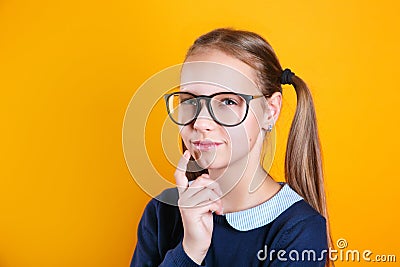 Pensive charming school girl 12 years old in glasses on yellow background Stock Photo
