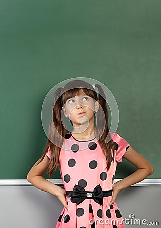 Pensive child girl near blank school blackboard Stock Photo