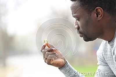 Pensive doubtful black man looking at wedding ring Stock Photo