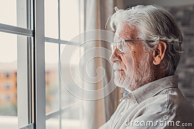 Pensive elderly mature senior man in eyeglasses looking in distance out of window, thinking of personal problems. Lost in thoughts Stock Photo