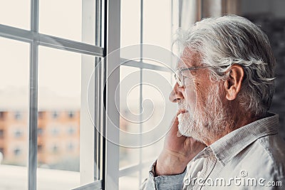 Pensive elderly mature senior man in eyeglasses looking in distance out of window, thinking of personal problems. Lost in thoughts Stock Photo