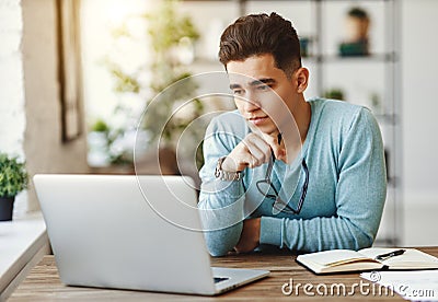 Pensive ethnic man using laptop at home Stock Photo