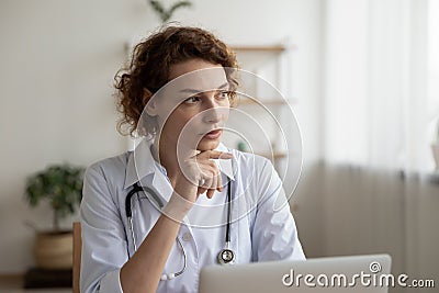 Pensive female doctor work on laptop thinking Stock Photo