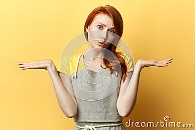 Pensive girl in gray apron doesn`t know the answer of the question Stock Photo