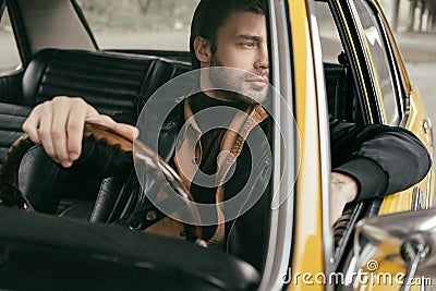 pensive handsome stylish man sitting in retro car and looking Stock Photo