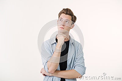 Pensive handsome young man wearing blue shirt over white background Stock Photo