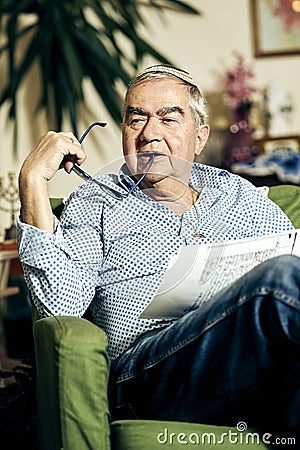 Pensive Jewish senior in the armchair reading a torah book Stock Photo