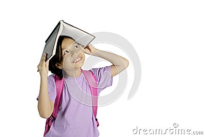 Pensive little girl putting a book on her head Stock Photo