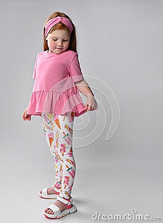 Pensive little red-haired girl child demonstrating summer fashion look Stock Photo