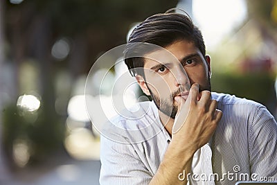 Pensive looking bearded young man sitting outside, portrait Stock Photo