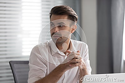 Pensive male employee look to side listen to coworker talk Stock Photo