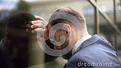 Pensive male leaning on office wall, work failure problem, disappointment Stock Photo