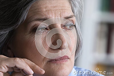 Pensive mature grey haired lady looking away in deep thought Stock Photo