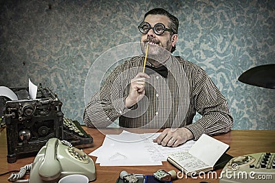 Pensive office employee with a pencil in his mouth looking up in Stock Photo