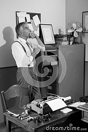 Pensive office worker looking for a file in the cabinet Stock Photo