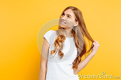 Pensive positive girl with a smile looks to the side, on a yellow background Stock Photo