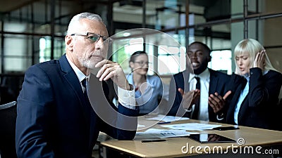 Pensive senior businessman thinking, nervous colleagues arguing, stress at work Stock Photo