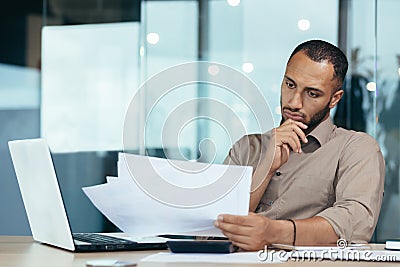Pensive serious businessman reading financial report, hispanic businessman holding document in hands looking Stock Photo