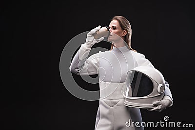 Pensive spacewoman is enjoying hot beverage Stock Photo