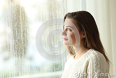 Pensive teenager looking through a window Stock Photo