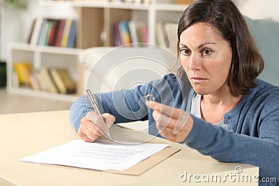 Pensive wife signing divorce papers looking away at home Stock Photo