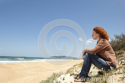 Pensive woman sitting on the dunes Stock Photo
