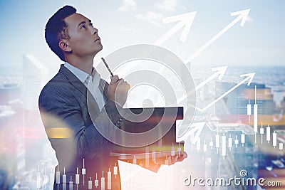 Thoughtful Asian man in city and graphs Stock Photo