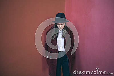 Pensive young teen girl stands against the red wall. Sad doubts. Melancholic mood to be alone with yourself Stock Photo