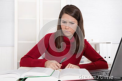 Pensive young trainee at desk - unhappy Stock Photo