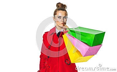 Pensive young woman in red coat on white with shopping bags Stock Photo