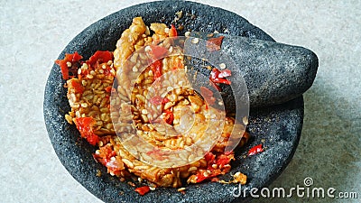 Penyet tempeh with chili sauce in a stone mortar Stock Photo