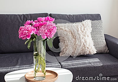 Peonies in the vase standing on the coffee table near the sofa Stock Photo
