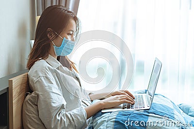 People Asian girl teen Coronavirus flu infected working at home by laptop computer online wear protective disposal face mask Stock Photo