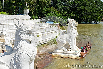 People bathing and washing on the riverbank of Irrawaddy River, next to chinthe statues, Burma Editorial Stock Photo