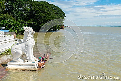 People bathing and washing on the riverbank of Irrawaddy River, next to chinthe statues, Burma Editorial Stock Photo