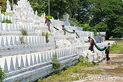 People bathing and washing on the riverbank of Irrawaddy River, next to chinthe statues, Burma Editorial Stock Photo