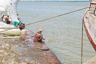 People bathing and washing on the riverbank of Irrawaddy River, next to chinthe statues, Burma Editorial Stock Photo