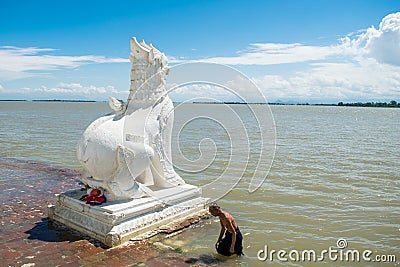 People bathing and washing on the riverbank of Irrawaddy River, next to chinthe statues, Burma Editorial Stock Photo