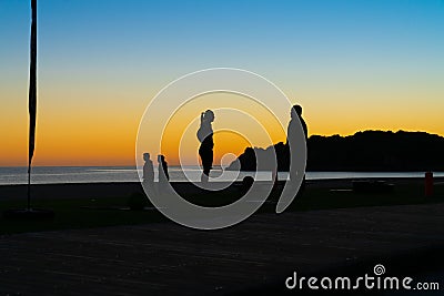 People on beach at Mount Maunganui at sunrise in silhouette doing morning fitnes exercise and walking by Editorial Stock Photo