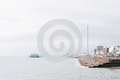 People on the beach and West Pier at Brighton, UK. Editorial Stock Photo