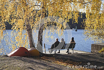 People on bench by water, framed in beautiful autumn colors. Editorial Stock Photo