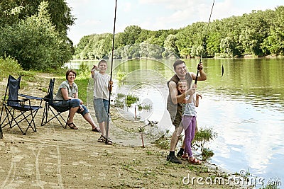 People camping and fishing, family active in nature, child caught fish on bait, river and forest, summer season Stock Photo