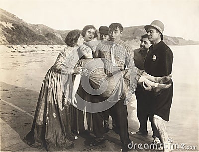 People carrying unconscious woman back to shore Stock Photo