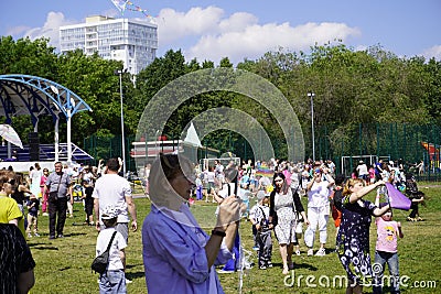 People celebrate the holiday of summer and childhood in the park, children and adults fly kites Editorial Stock Photo