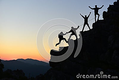 People climbing rock at sunset Stock Photo