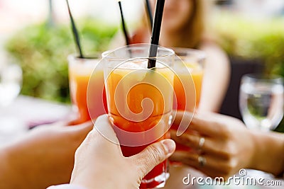 People clinking glasses with cocktail, aperol and wine on the summer terrace of cafe or restaurant. Women friends having Stock Photo